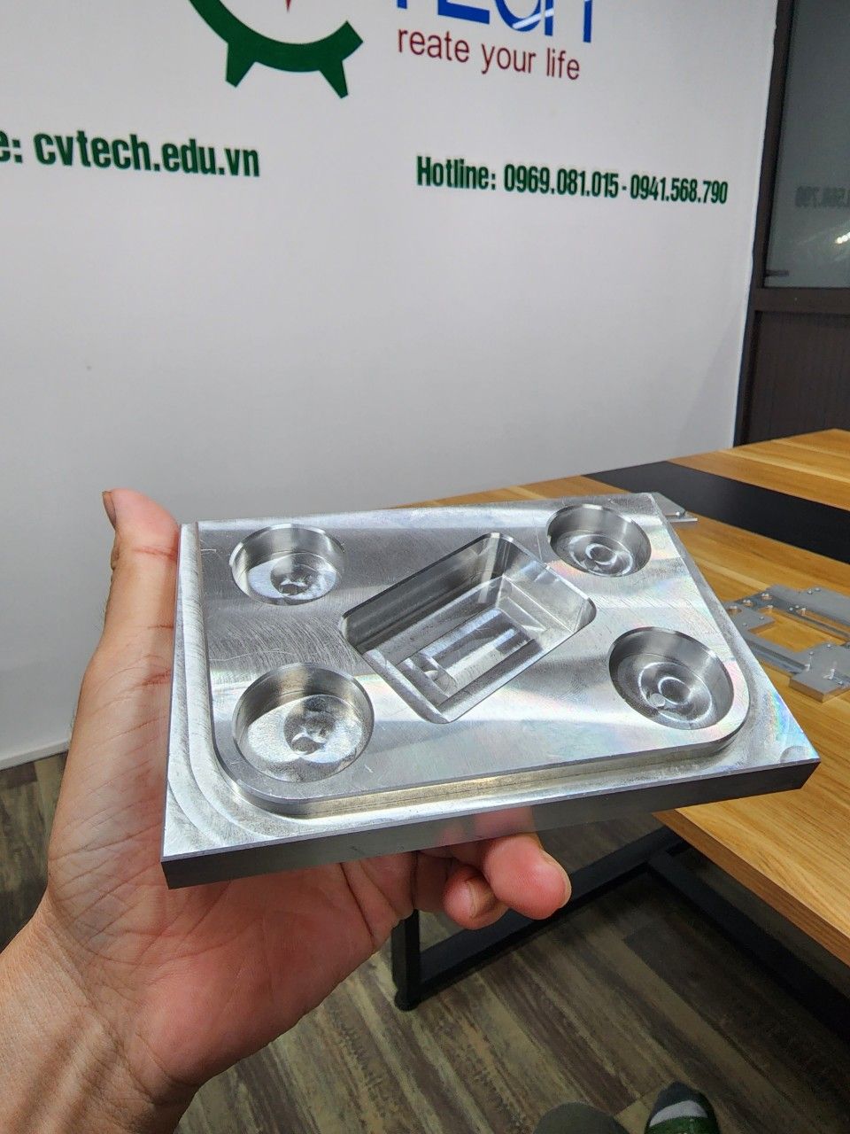 Chi tiết nhôm phay có bốn lỗ cầm trên tay - cách sử dụng panme