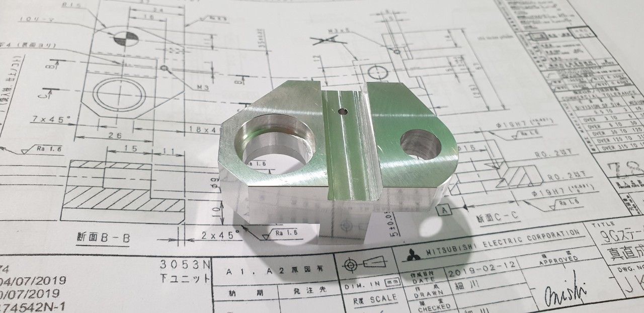 Chi tiết nhôm phay đặt trên tờ bản vẽ kỹ thuật - bản vẽ kỹ thuật là gì
