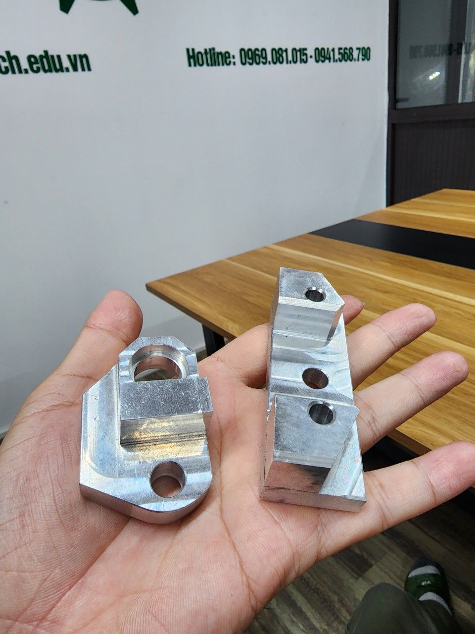Hai chi tiết nhôm nhỏ gia công cầm trên tay - gia công cắt gọt kim loại