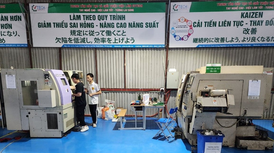 Học viên đứng cạnh máy tiện CNC trong xưởng - học nghề gia công cơ khí cnc