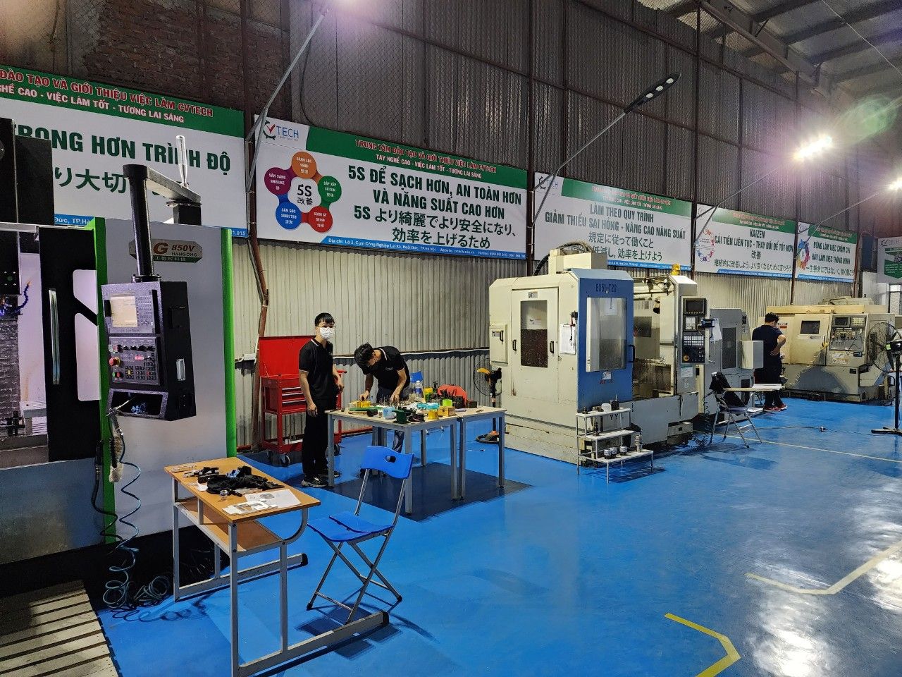 Học viên làm việc bên máy phay CNC, ảnh chụp từ trên cao - bước tiến dao