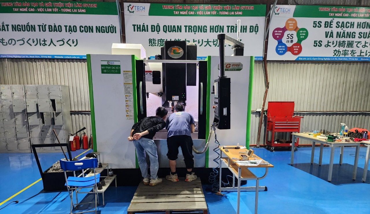 Ba người đứng trước máy phay CNC trong xưởng - lệnh g00