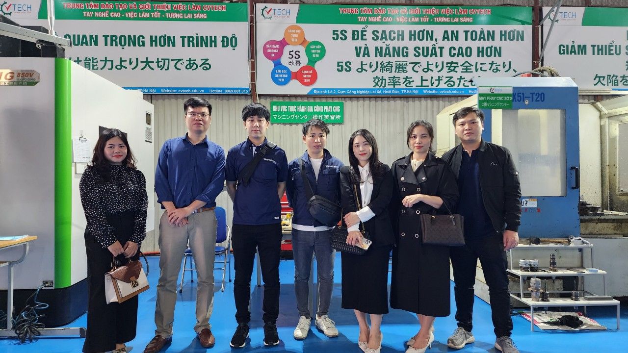 Nhóm người đứng chụp ảnh cạnh máy phay CNC trong xưởng - santomas việt nam