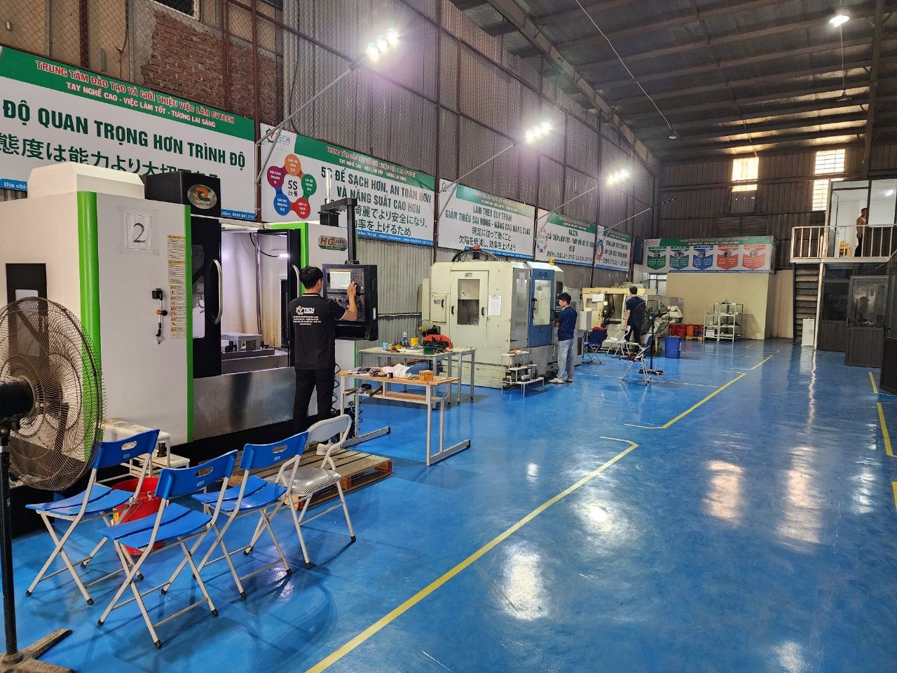 Máy phay CNC viền xanh lá trong xưởng, có ghế xếp cho học viên quan sát - cấu tạo máy phay cnc