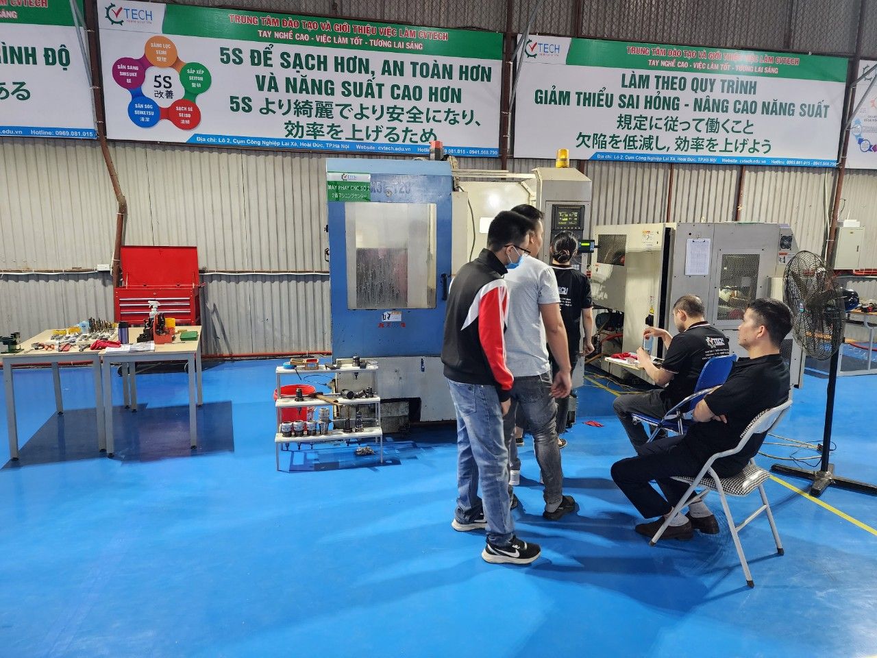 Nhóm học viên ngồi và đứng cạnh máy tiện trong xưởng - cuộc thi ảnh cvtech star