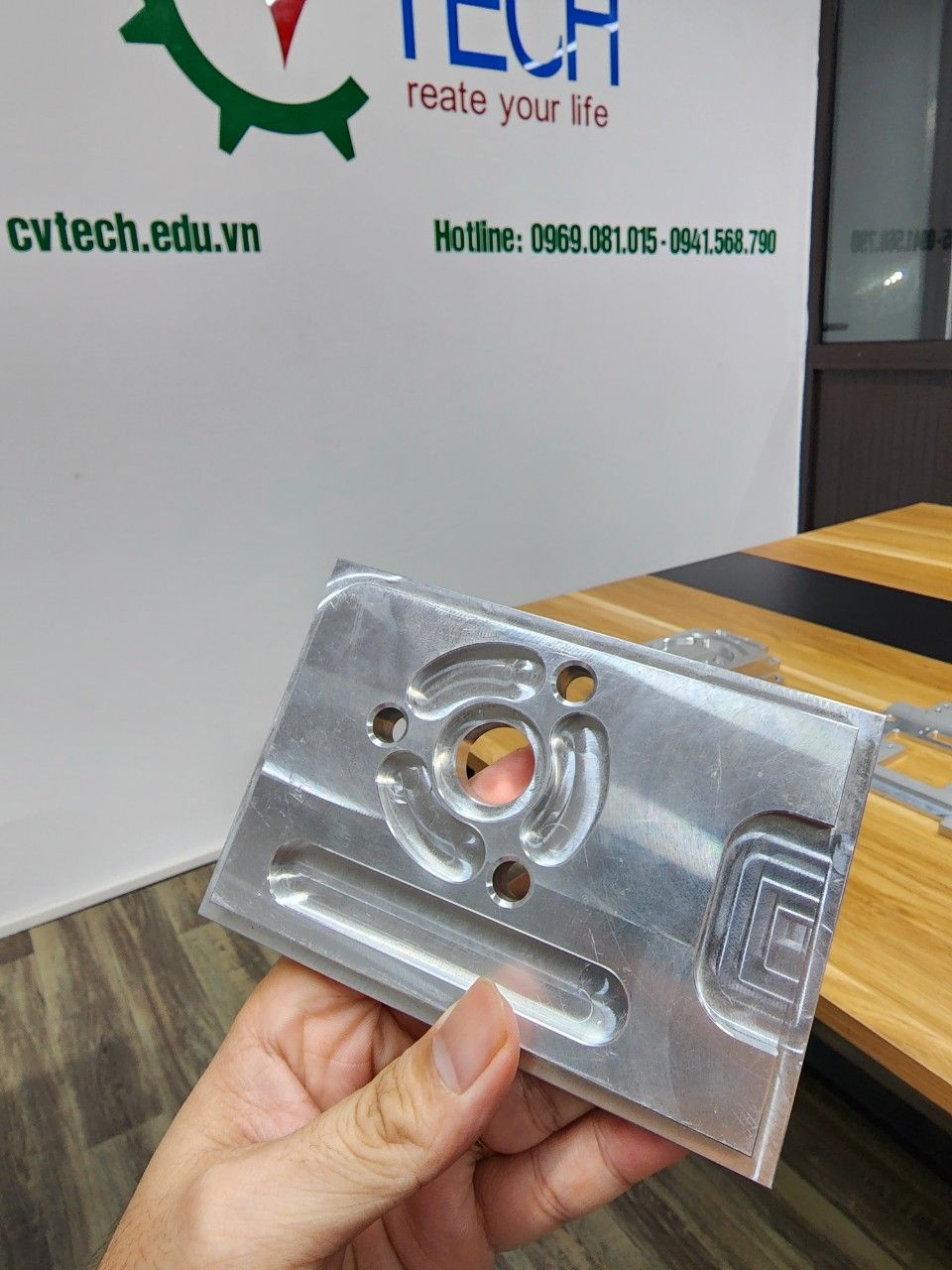 Tấm nhôm phay có lỗ và rãnh cầm trên tay - thước cặp cơ khí
