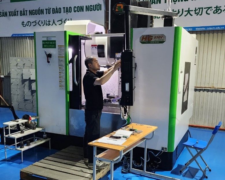 Người thao tác trên bảng điều khiển máy phay CNC viền xanh lá