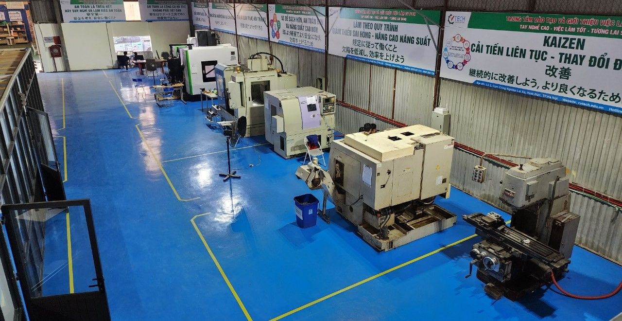 Toàn cảnh xưởng thực hành với dãy máy tiện và máy phay CNC, sàn xanh dương - ngành cơ khí
