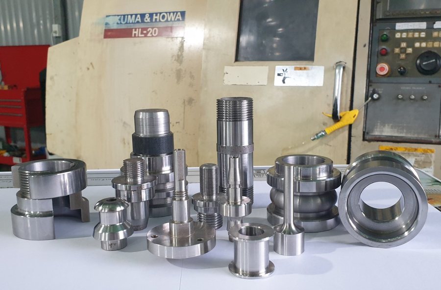 Nhiều chi tiết tiện xếp trước bảng điều khiển máy - dao tiện
