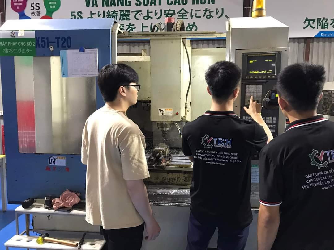 Học viên đứng trước bảng điều khiển máy phay CNC